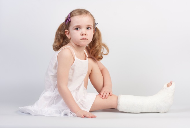 Little girl injured with broken ankle sitting on white backgound.